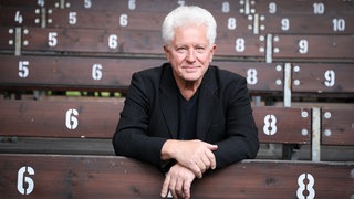 Schauspieler Miroslav Nemec sitzt auf einer Tribüne. In SWR1 Leute spricht er über seine Rolle des Kriminalhauptkommissar Ivo Batic im Tatort München.