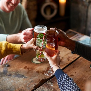 Freunde stoßen in einer Kneipe mit alkoholischen Getränken an.