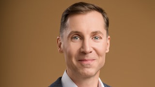 Plastischer Chirurg Dr. Stéphane Stahl schaut direkt in die Kamera.