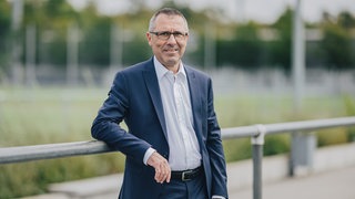 Der ehemalige Präsident der TSG 1899 Hoffenheim schaut freundlich in die Kamera.