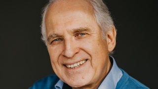 Zeichner und Autor Werner Tiki Küstenmacher lacht in die Kamera. 