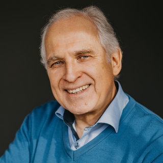 Zeichner und Autor Werner Tiki Küstenmacher lacht in die Kamera. 