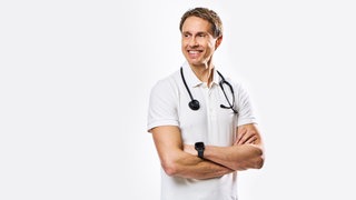 Dr. Tim Hollstein, Stoffwechselspezialist und Ernährungsmediziner, steht da mit verscrhänkten Armen und umgehängten Stetoskop