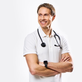 Dr. Tim Hollstein, Stoffwechselspezialist und Ernährungsmediziner, steht da mit verscrhänkten Armen und umgehängten Stetoskop
