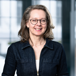 Finanzcoachin Dani Parthum schaut in die Kamera und lächelt.