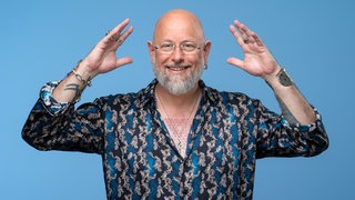 Hypnotiseur und Bühnenkünstler Jan Becker macht eine Pose und lacht in die Kamera.