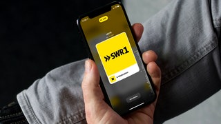 Mann nutzt SWR1 App auf seinem Smartphone