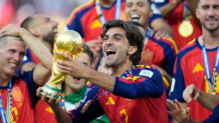 20. Juli: Da ist es! Zum Ende jeder Fußball-WM gehört dieses Bild. Jubelnde Spieler, in diesem Fall die Spanier, halten den Pokal in ihren Händen. Hier im Mittelpunkt: Ferran Torres, der das einzige Tor im Finale schoss. Nicht im Bild: Lionel Messi. Für den Argentinier und Weltmeister von 2022 gab es 2026 kein weltmeisterliches Foto mit der Trophäe.
