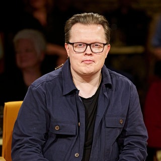 Angelo Kelly hat ein blaues Hemd an und schaut direkt in die Kamera