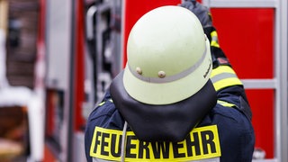 Ein Feuerwehrmann zieht einen Schlauch aus einem Löschwagen (Symbolbild).