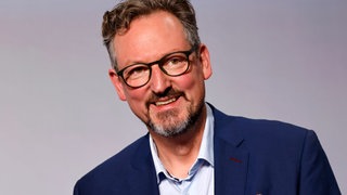 Dr. Eckart von Hirschhausen lächelt mit gesenktem Kopf
