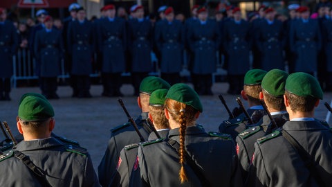 Sonnenlicht fällt beim feierlichen Gelöbnis der Bundeswehr auf dem Marktplatz in Haldensleben auf Soldaten und Soldatinnen der Ehrenformation. Im Hintergrund sind Rekruten und Rekrutinnen der Bundeswehr zu sehen.