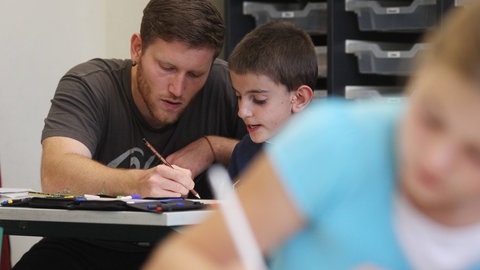 Inklusionsarbeit an einer integrierten Gesamtschule. Integrationskraft mit Schüler an Schulbank