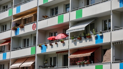 Ein Mehrfamilienhaus mit Balkonen, mit Markisen und Sonnenschirmen.