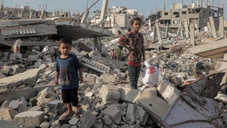 Ein kleiner Junge steht auf einem Trümmerhaufen. Kriegsalltag in Gaza.