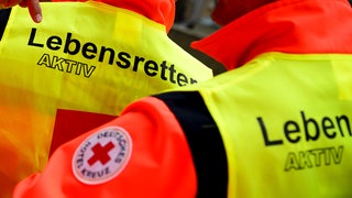 Mitarbeiter des Deutschen Roten Kreuzes (DRK) tragen bei einer Demonstration Westen mit der Aufschrift "Lebensretter aktiv".