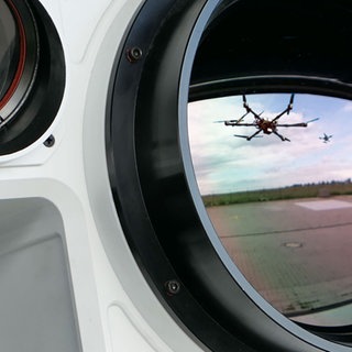 Eine Drohne und eine Abfangdrohne spiegeln sich in der Linse eines mobilen Detektionssystems zur Drohnenabwehr.