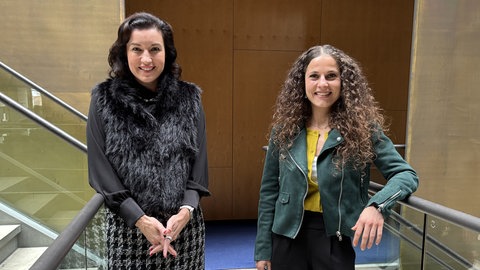 Forschungsministerin Dorothee Bär und Korrespondentin Sarah Beham stehen in der Halle im ARD-Hauptstadtstudio nebeneinander und schauen in die Kamera