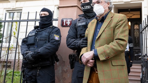 Aufnahme 07.02.2022: Bei einer Razzia gegen sogenannte "Reichsbürger" führen vermummte Polizisten, nach der Durchsuchung eines Hauses Heinrich XIII Prinz Reuß (r) zu einem Polizeifahrzeug.
