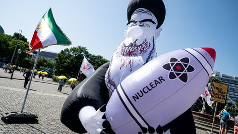 Ein aufblasbarer und zur Fratze verfremdeter Ayatolla Ali Chamenei, der eine Atomrakete im Arm hält.