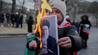Ein Demonstrant hält ein brennendes Plakat des Obersten Führers des Irans, Ayatollah Ali Khamenei, während einer Kundgebung zur Unterstützung der landesweiten Massendemonstrationen im Iran gegen die Regierung.