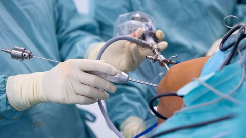 Ein Arzt operiert einen Patienten mit komplizierten medizinischen Geräten am Knie.
