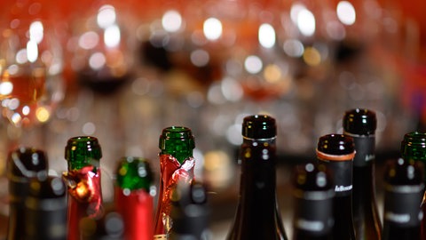 Leere Wein- und Sektflaschen stehen in einer Bar auf einem Tresen.