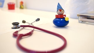 Ein Stethoskop und Kinderspielzeug liegen in einer Kinderarztpraxis auf einem Tisch