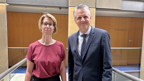 Korrespondentin Katrin Aue und Unionsfraktionschef Thorsten Frei stehen in der Halle des ARD Hauptstadtstudios nebeneinander und lächeln in die Kamera