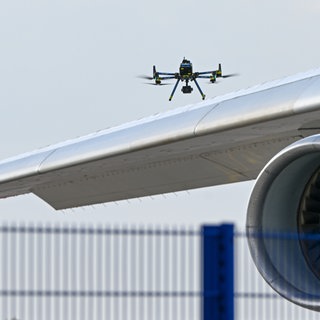 Eine Drohne der Polizei ist über einer Flugzeugtragfläche zu sehen.