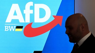 Markus Frohnmaier, der Spitzenkandidat der AfD Baden-Württemberg für die Landtagswahl 2026, läuft am Logo der Partei AfD vorbei.