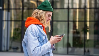 Hipster-Typ, der draußen auf den Bildschirm seines Smartphone schaut