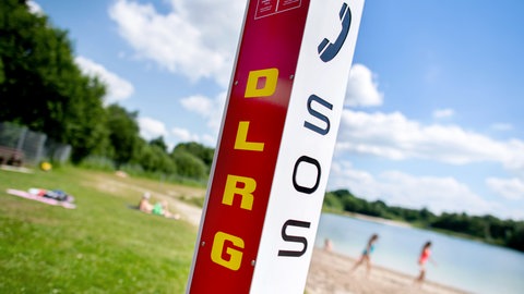Eine Notrufsäule der DLRG steht an einem Badesee.