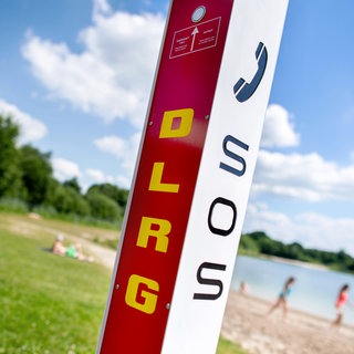 Eine Notrufsäule der DLRG steht an einem Badesee.