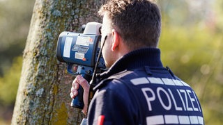Ein Polizist kontrolliert mit einem Lasergerät an der Bundesstraße 36 die Geschwindigkeit von Fahrzeugen. 