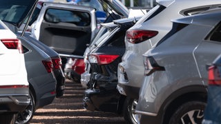 Neuwagen und Gebrauchtwagen stehen bei einem Autohändler nebeneinander. 