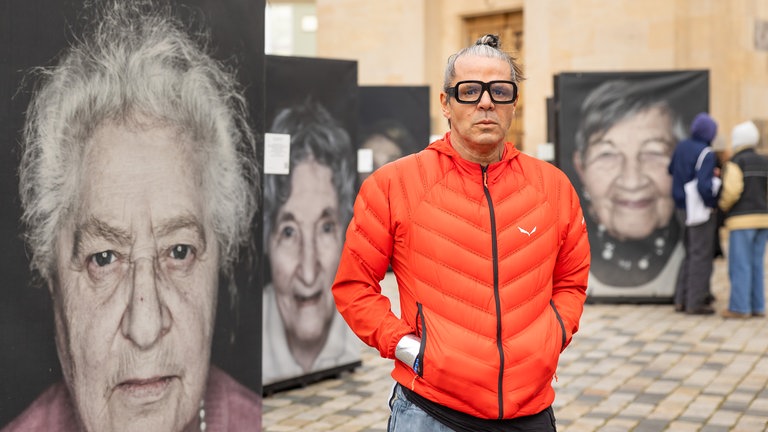 Der Fotograf Luigi Toscano steht vor großformatigen Bildern seiner Ausstellung "Gegen das Vergessen" auf dem Neumarkt vor der Frauenkirche Dresden. Zu sehen sind 80 großformatige Bilder von Holocaust-Überlebenden. Die Portraits sind Teil eines internationalen Erinnerungsprojekts von Luigi Toscano.