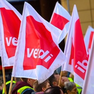 Streikende halten Flaggen der Gewerkschaft ver.di in die Luft. In Baden-Württemberg gibt es zahlreiche Warnstreiks im öffentlichen Dienst.