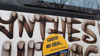 Ein Aufkleber auf einem Graffiti, mit dem ein Waggon der Südwestdeutschen Landesverkehrs-GmbH (SWEG) beschmiert ist.