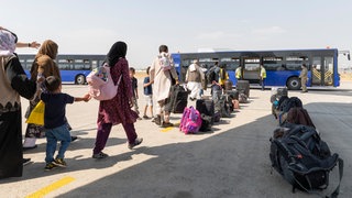 (Symbolbild) Afghanische Flüchtlinge gehen kurz nach einem Evakuierungsflug aus Kabul zu einem Bus. Im Rahmen eines Bundesaufnahmeprogramms konnten "besonders gefährdete" Menschen aus Afghanistan nach Deutschland fliehen. Die Zahlen der Geflüchteten nehmen aber seit Jahren ab auch in Baden-Württemberg.