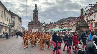 Verkleidete Menschen laufen am Schmutzigen Donnerstag zum Rathaussturm in Rastatt.
