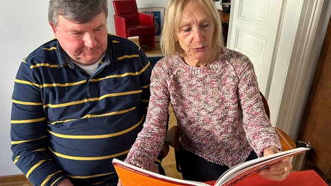 Kazmaier und Wessels blättern in einem Buch