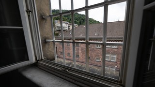 Ein Gebäude des Ex-Gefängnisses "Fauler Pelz" in der Heidelberger Altstadt ist durch ein vergittertes Fenster zu sehen. 