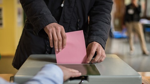 Ein Umschlag mit Stimmzettel wird bei einer Landtagswahl in Baden-Württemberg in die Wahlurne geworfen.