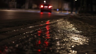 Mit einer dünnen Eisschicht überzogen ist eine Straße am frühen Morgen.
