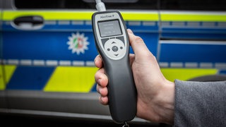 Ein Alkoholtestgerät vor einem Polizeiwagen (Symbolbild).