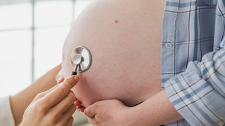 Arzt untersucht schwangere Frau hält Stethoskop in der Nähe von großen Bauch