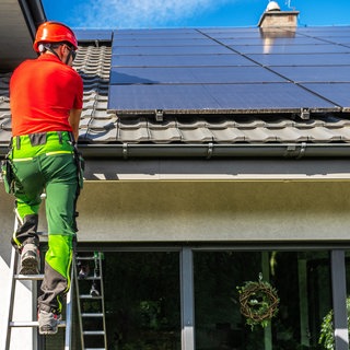 Installateur montiert Solarpanele auf einem privaten Hausdach