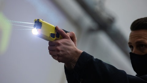 Ein Polizeibeamter demonstriert einen Schuss mit einem Taser.