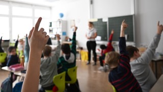 Schülerinnen und Schüler heben in einer Klasse die Hand. In Baden-Württemberg sollen nun die 1.440 Lehrerstellen besetzt werden. (Symbolbild)